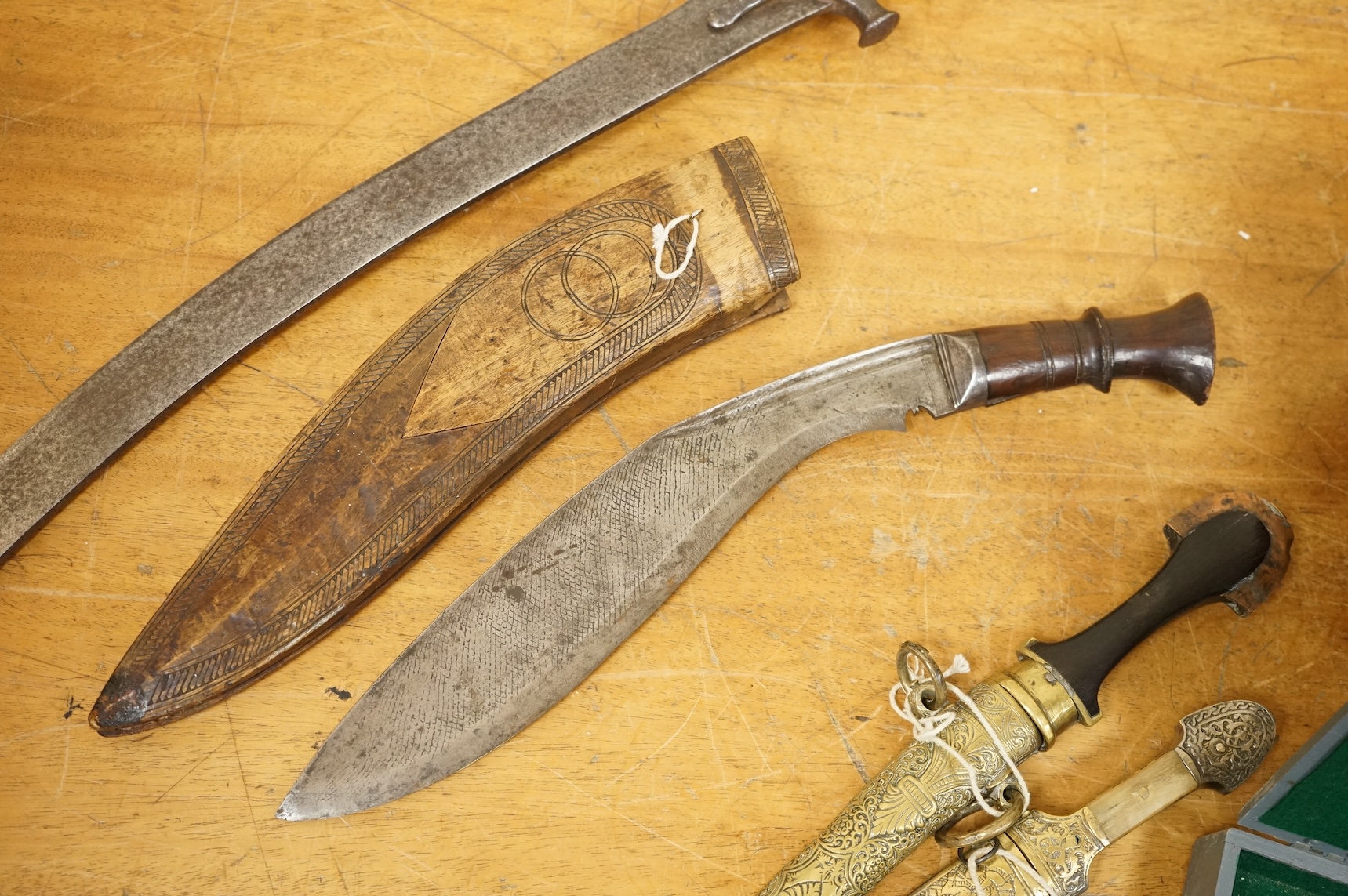 An Indian sword tulwar, the iron hilt with traces of chiselled and inlaid decoration, together with a kukri in its wooden scabbard, a Syrian jambya and a Moroccan jambiya (4)